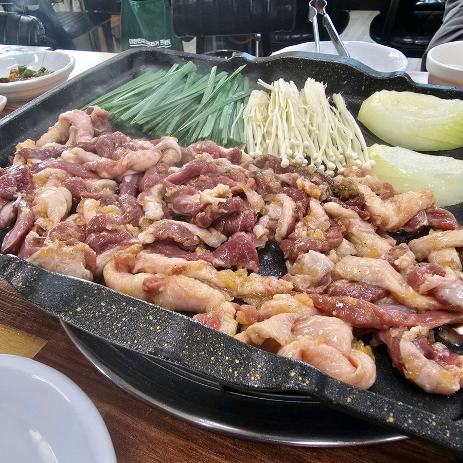 불판 위에 생오리와 팽이버섯, 부추, 양파를 올린 갈릭로스